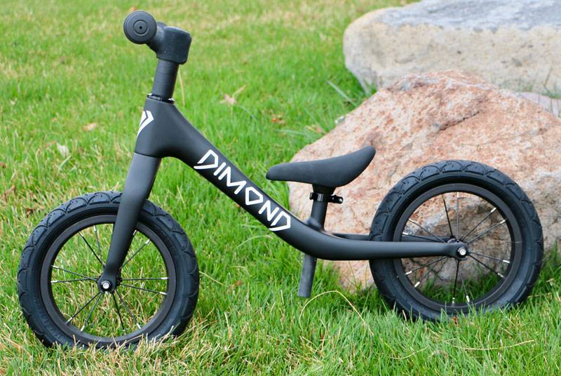 Beautiful Dimond Miner black balance bike set against a grass background.