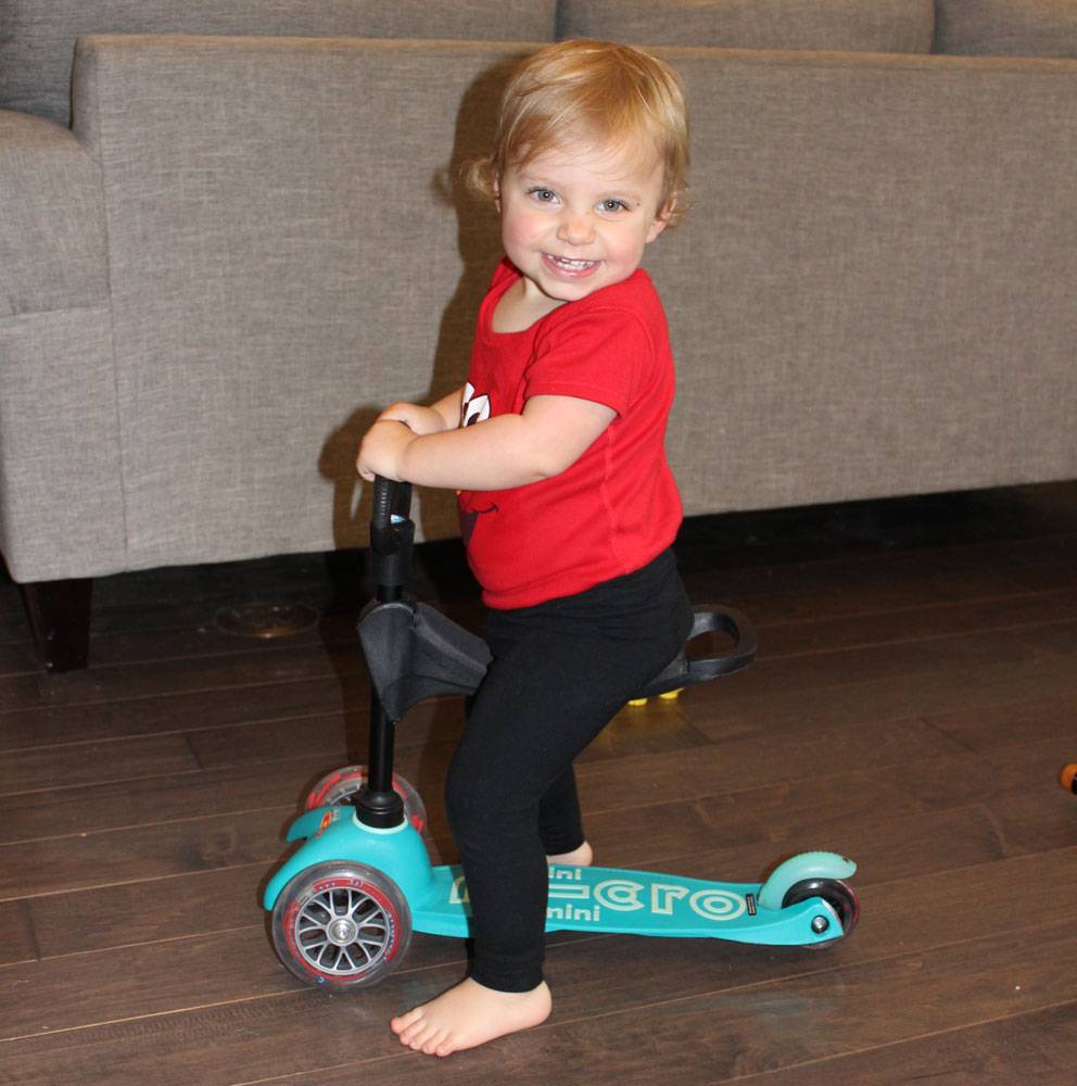 toddler riding 3 wheel scooter indoors