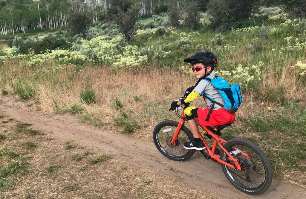 7 year old boy riding an orange pello rover kids 20 inch bike