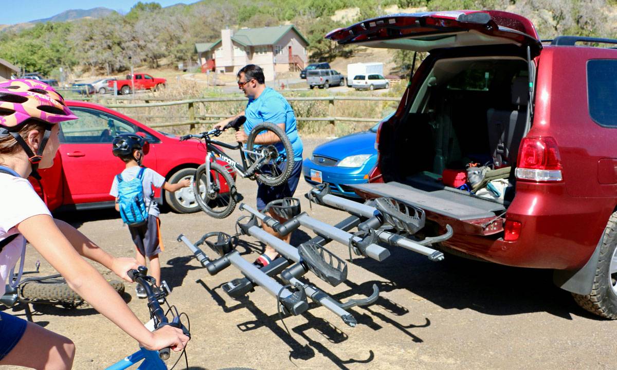 thule t2 pro bike rack tilt down access. Dad is unloading bikes and handing them to kids.