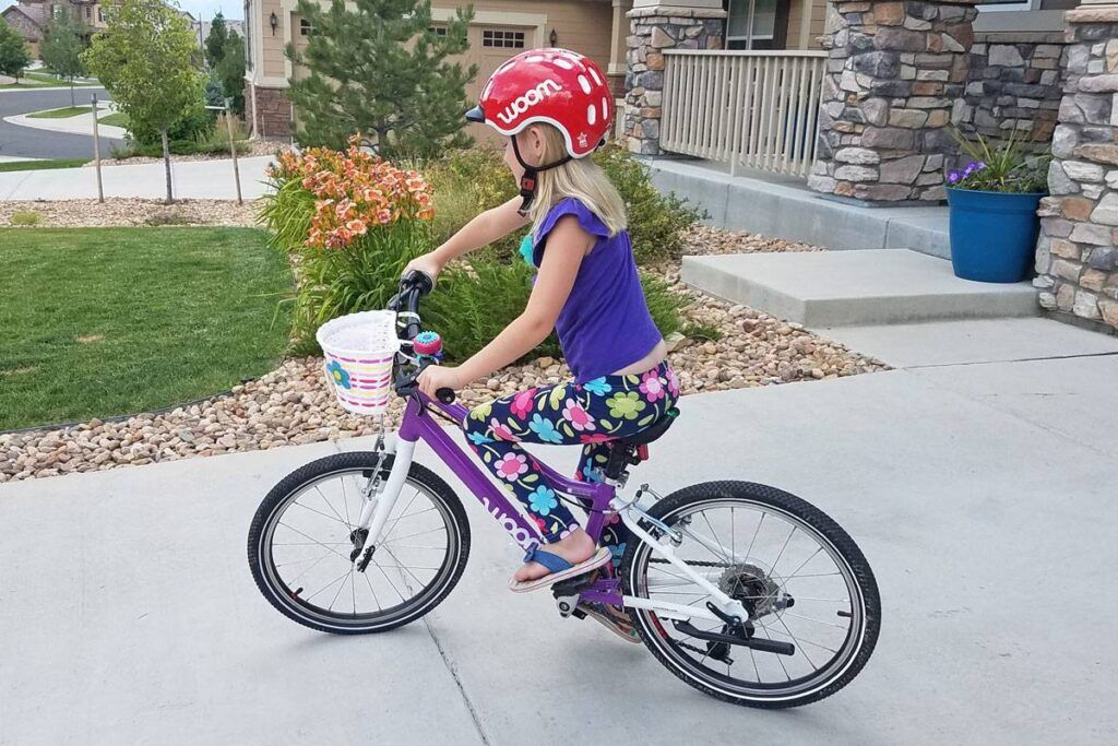 7 year old girl riding woom 4 in her driveway with the Schwinn kids bike basket attached to her handlebars