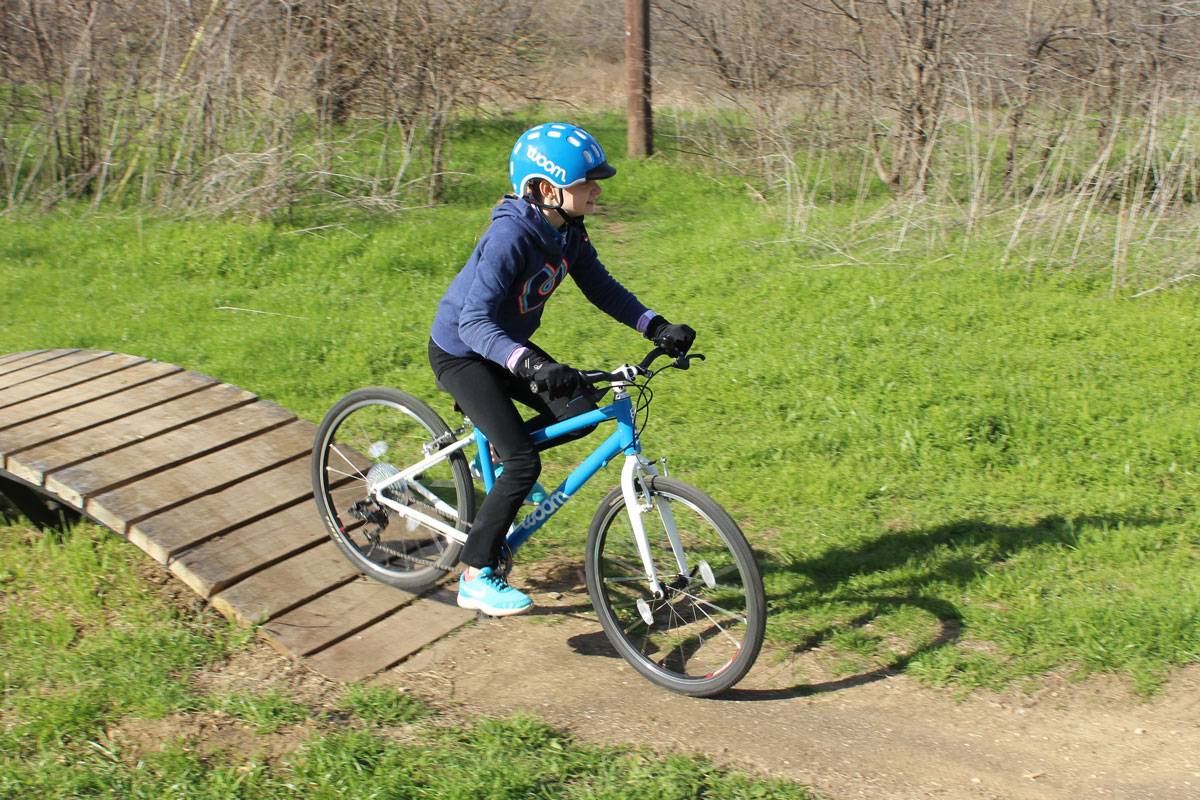 child riding a blue woom 5 at a bike park