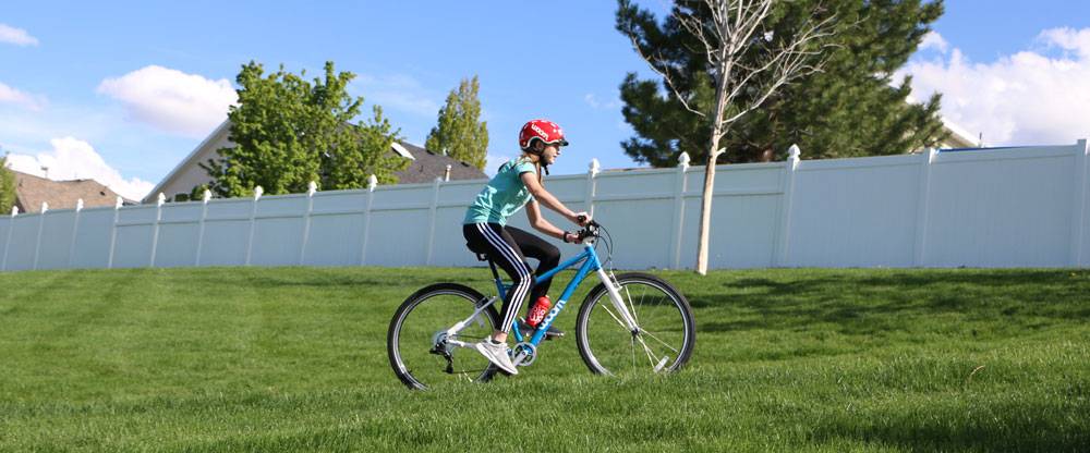 tween girl riding the woom 6 down a paved trail
