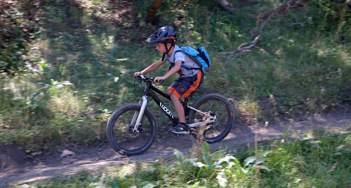 young boy riding a trail on the woom OFF 4 mountain bike