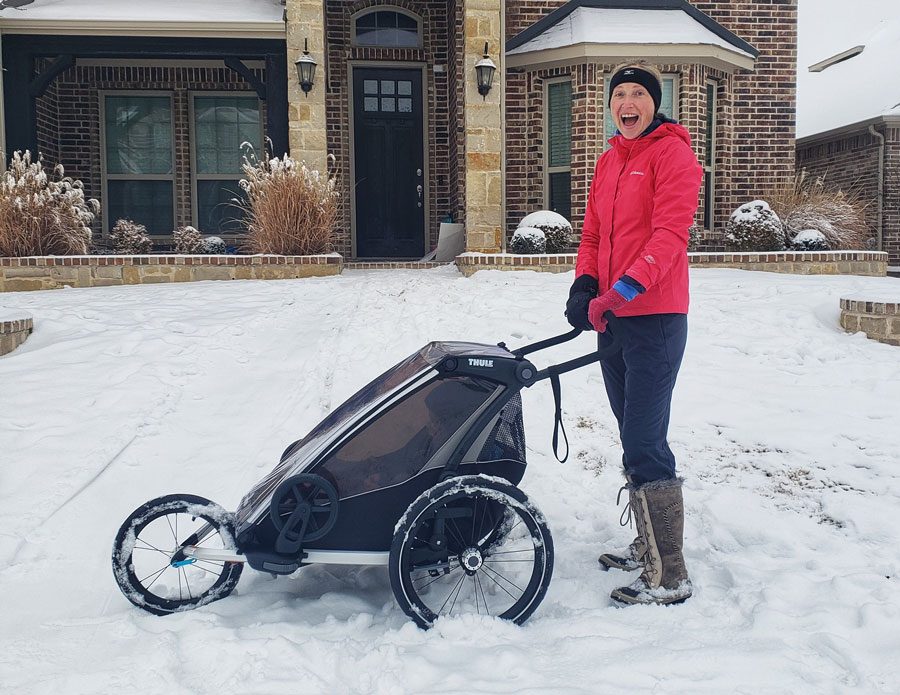 Mom pushing Thule Chariot Lite in jogger mode through the snow