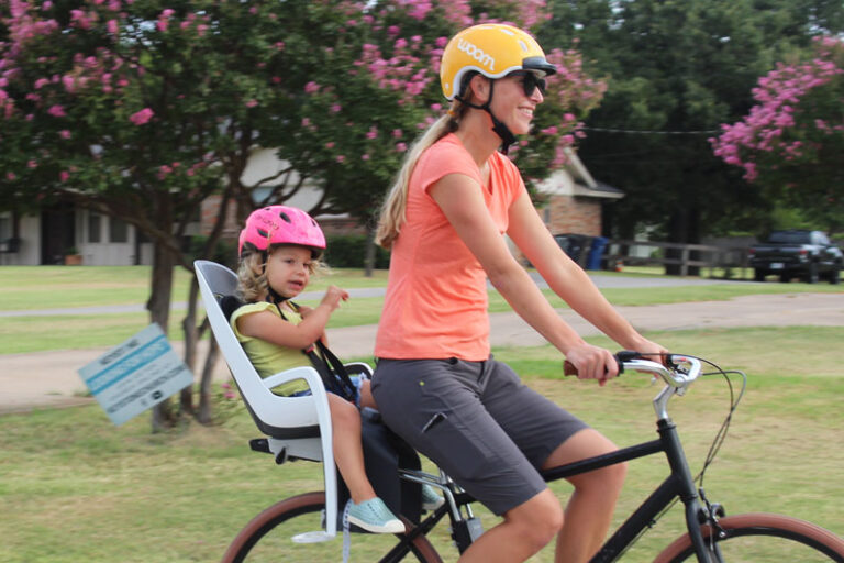 Mom and toddler riding with Hamax Caress child bike seat and Priority Bicycles adult bike