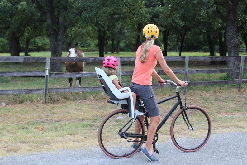 Mom and toddler watching a horse while riding a bike and using the Hamax Caress child bike seat