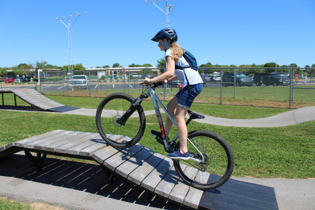11 year old girl riding Marin Wildcat Trail 3 XS hardtail mountain bike up wood bridge feature at Runway Bike Park