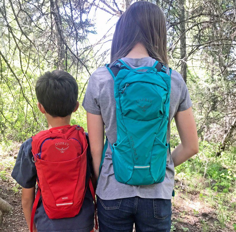 a boy wearing an Osprey Moki hydration pack next to a girl wearing a Osprey Kitsuma hydration pack
