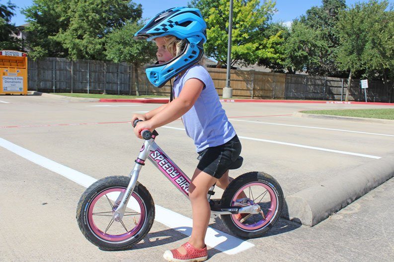 2.5 year old riding her Strider balance bike and wearing the Strider Full Face Helmet with the chin guard
