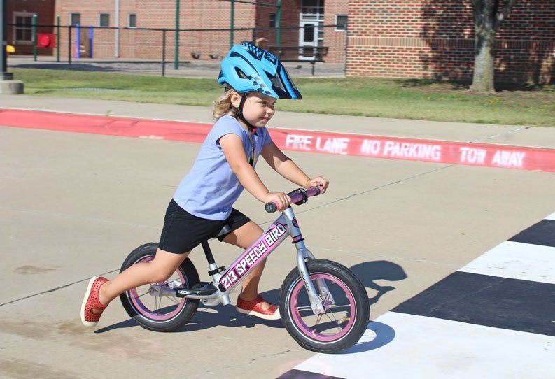 2.5 year old riding her Strider balance bike and wearing the Strider Full Face Helmet without the chin guard