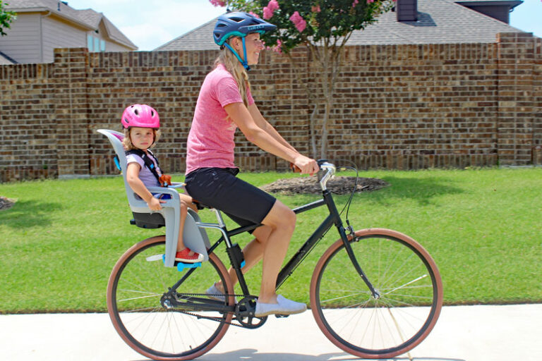 Mom riding Priority bicycle with toddler on the back in Thule RideAlong child bike seat.