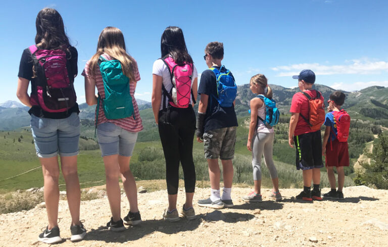 Group of 7 children on a mountain wearing hydration packs