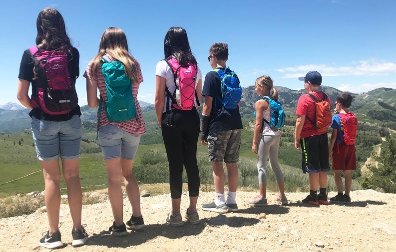 Group of 7 children on a mountain wearing hydration packs