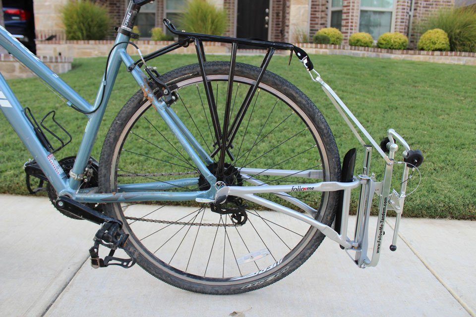 FollowMe Tandem folded up and attached to the back of the adult bike via a rope and carabiner on the rack