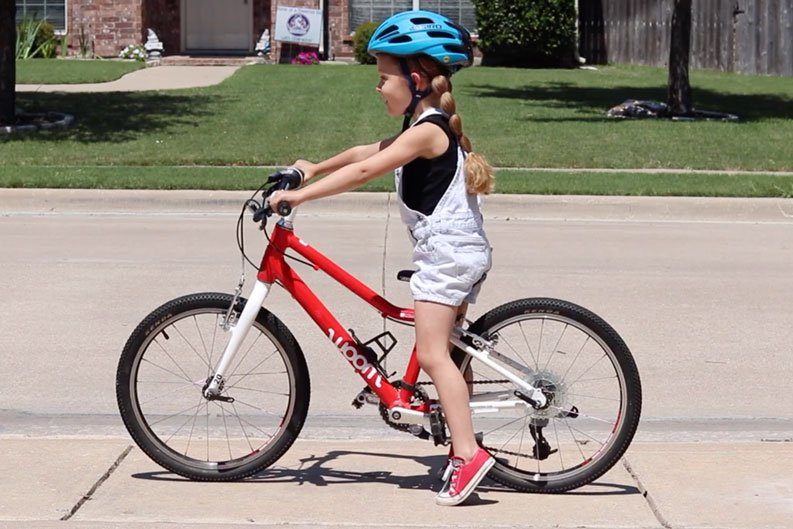 5 year old rider sitting on her bike with her feet touching the ground on her tip toes