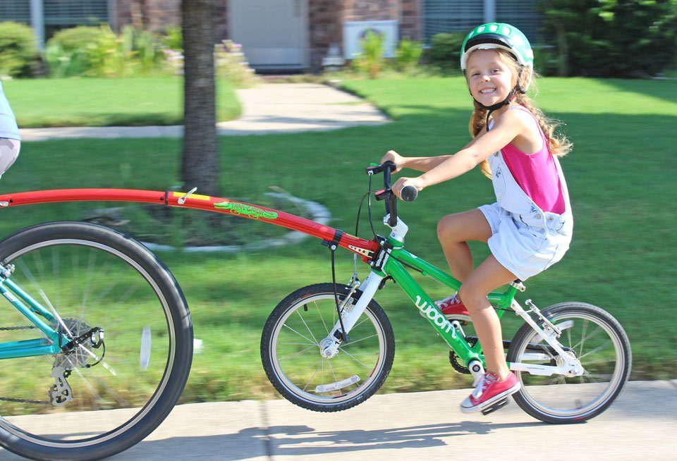 Child smiling while being towed on trail gator tow bar.