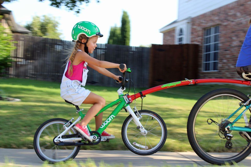 5 year old being pulled by her mom on her bike using the Trail Gator tow bar.