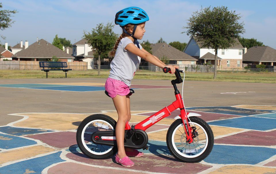 5 year old standing over the saddle of the SmarTrike Xtend convertible balance bike to show sizing