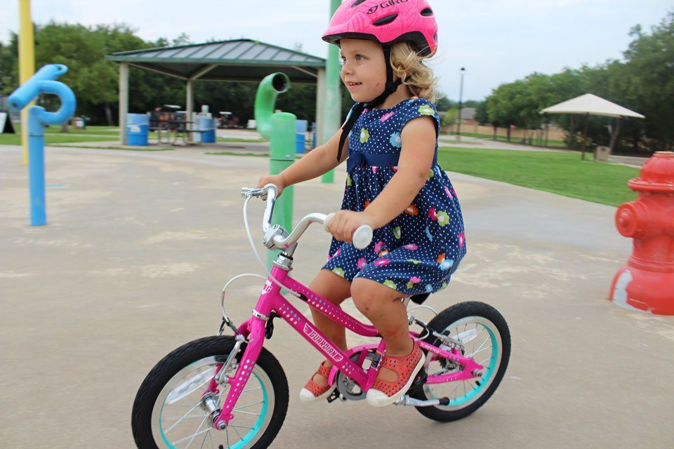 child riding Guardian Ethos 14 girls bike through splash pad