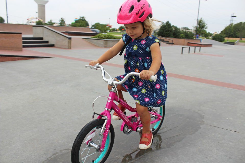 Young girl riding Guardian 14 inch bike through a puddle