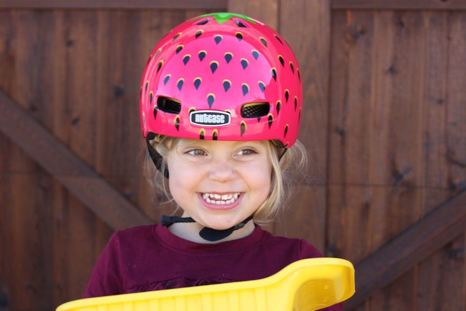 Toddler smiling and wearing the Nutcase Baby Nutty bike helmet
