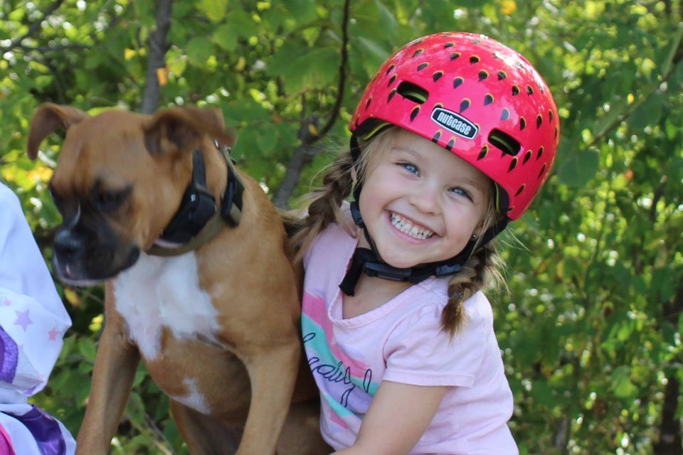 3 year old wearing Nutcase Baby Nutty helmet while sitting with her dog