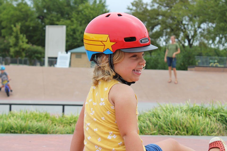 2 year old wearing Nutcase Little Nutty helmet with Wonder Woman pattern. At the skatepark.