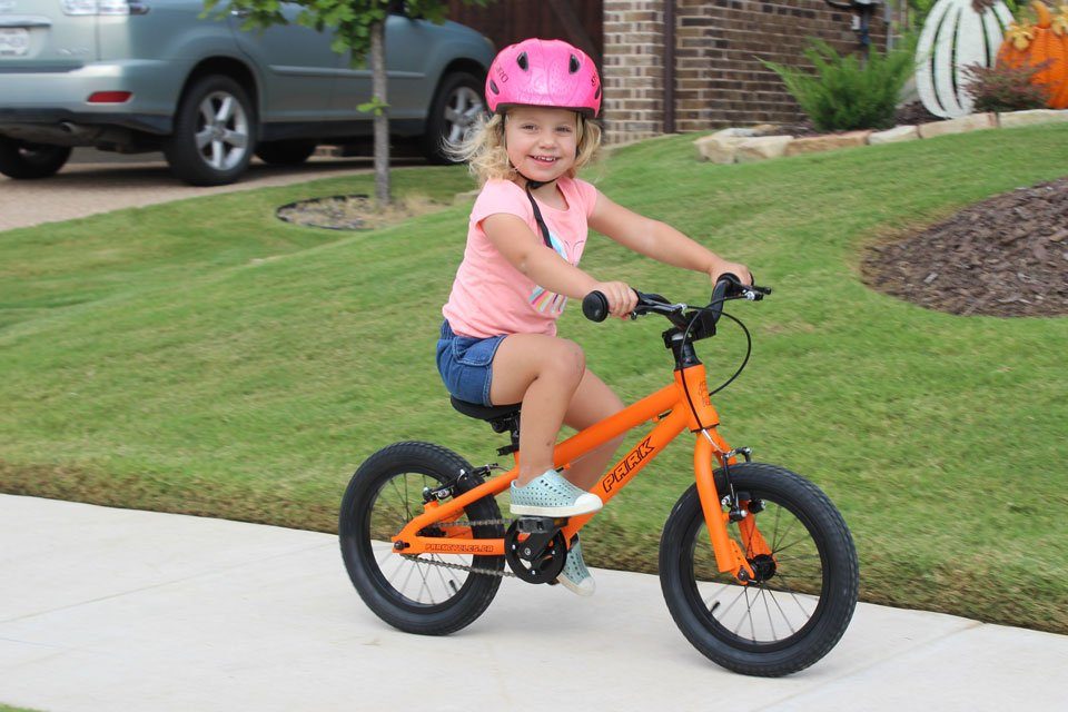 2 year old riding Park Cycles 14 kids bike down the street in her neighborhood