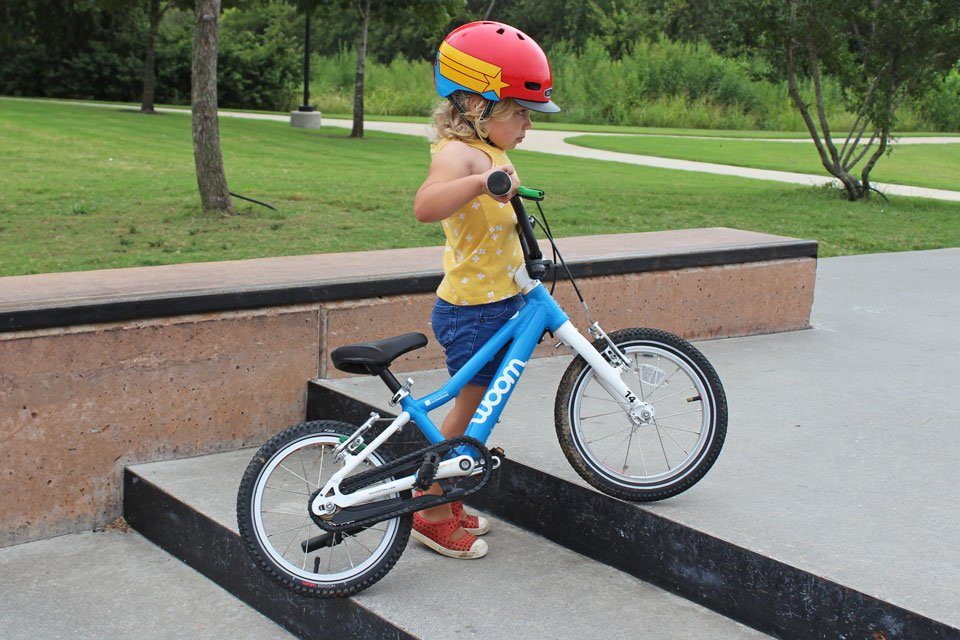 Child lifting woom 2 bike up the stairs at the skatepark