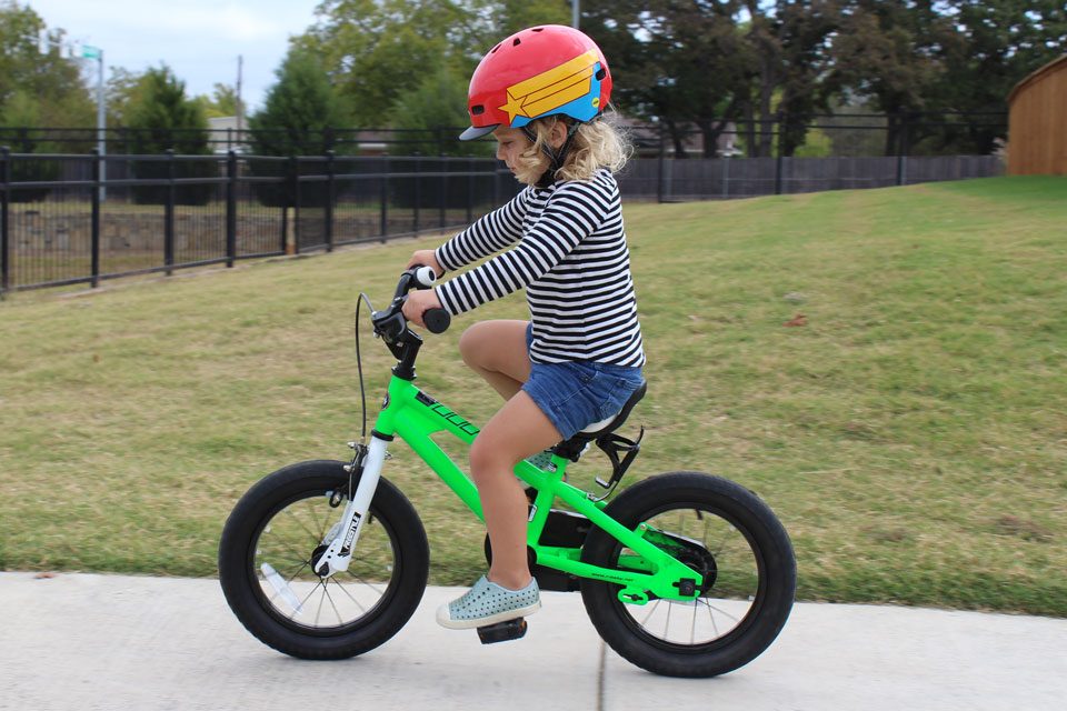 3 year old happily riding the Royal Baby Bike down the sidewalk, shot from side