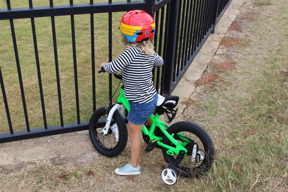 Young girl rider after a crash into a gate with the training wheels on the Royalbaby bike