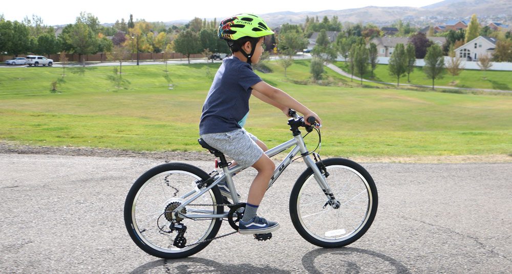 6 year old riding Vitus Kids 20 inch bike down a paved road