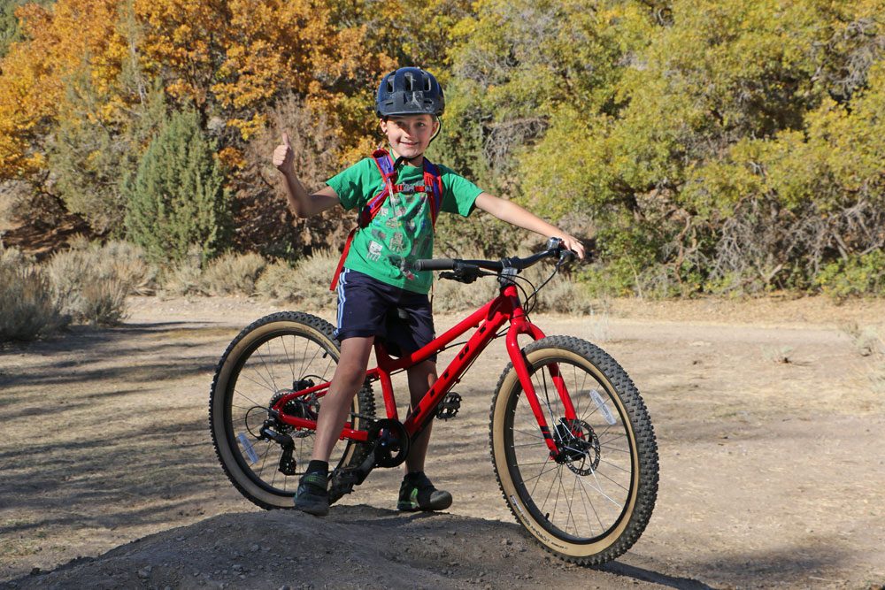 8 year old standing with Vitus Plus 24 inch kids bike and giving a big thumbs up