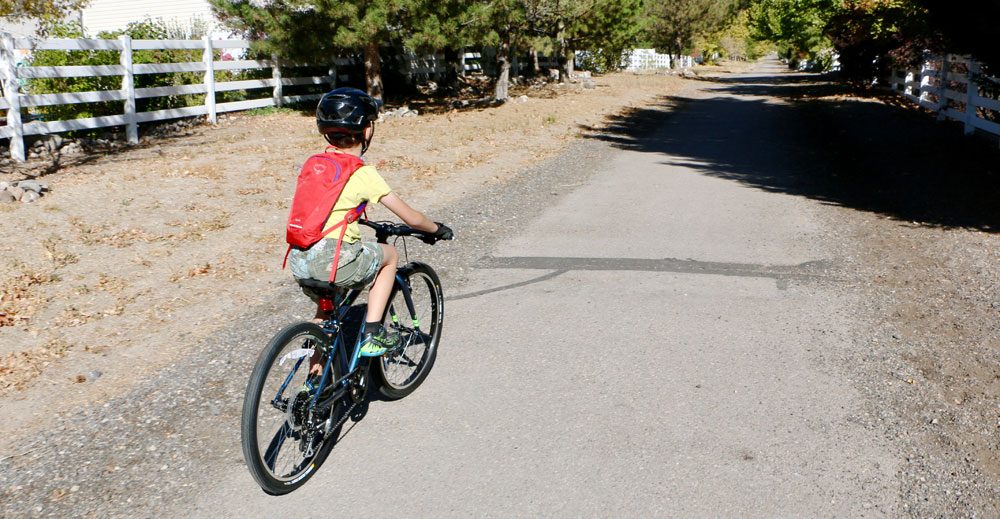 8 year old riding Vitus Kids 24 inch bike down a gravel trail