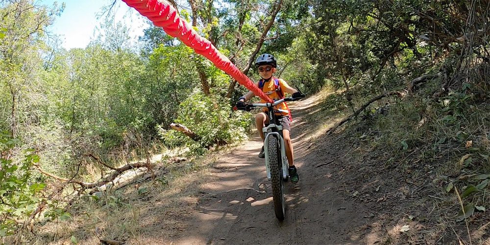 Child being pulled straight behind his mom's mountain bike using the TowWhee tow rope.