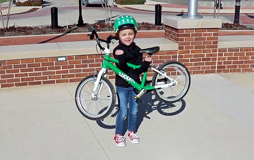 young child holding up her lightweight woom kids bike