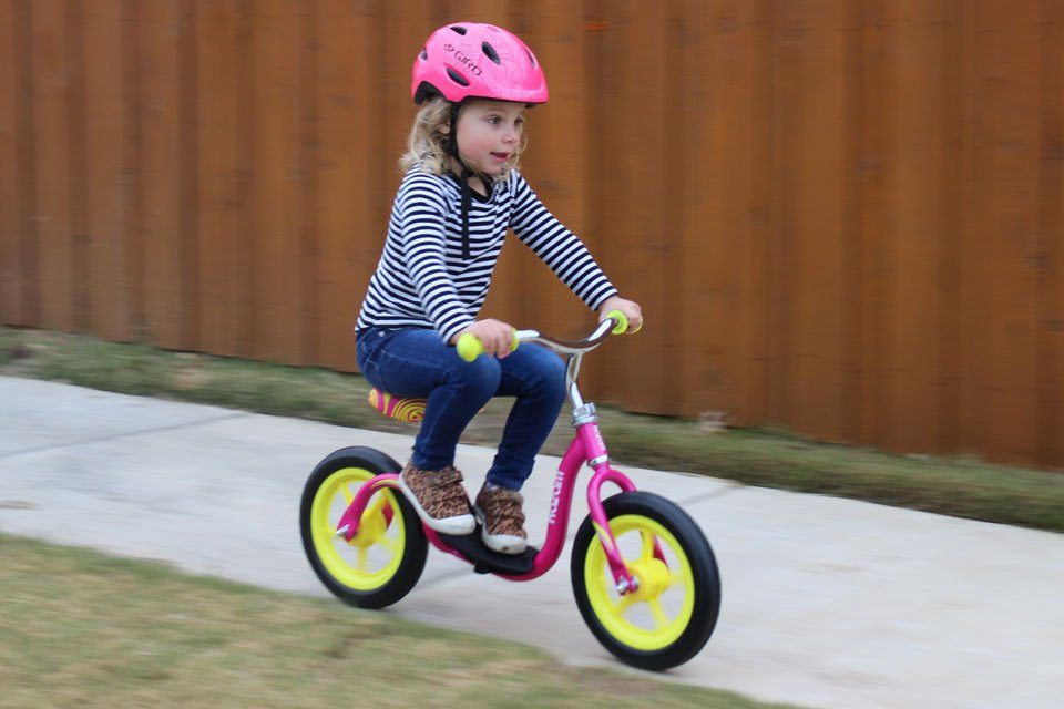 Young child riding the Kazam and resting her feet on the footrest.