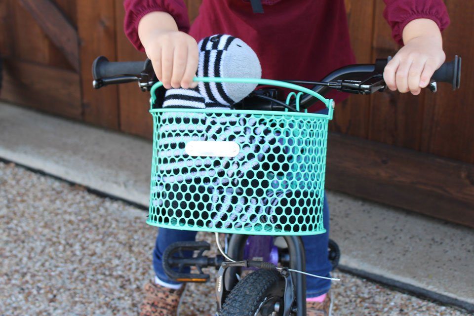Turquoise mesh bike basket with child lifting up the handle