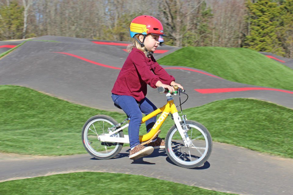 Toddler riding a balance bike at a pump track