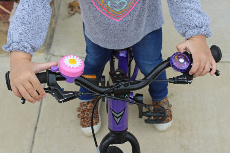 Child on bike with a bike bell on the left hand and the right hand