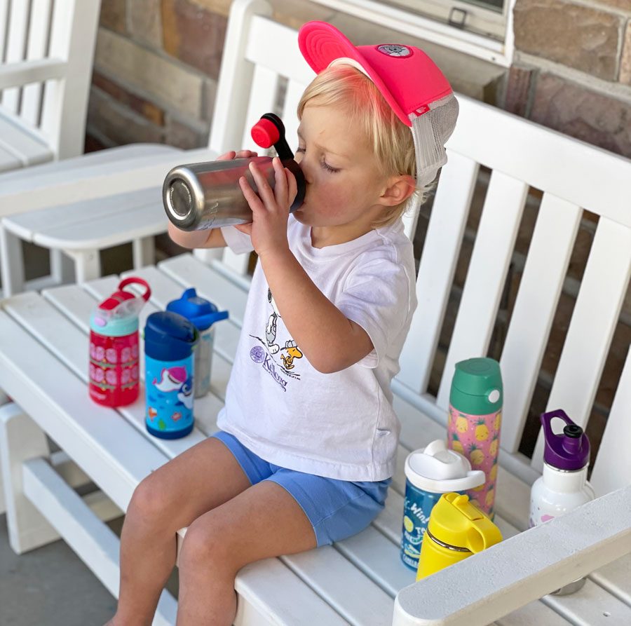 Child sitting on a bench surrounded by water bottles