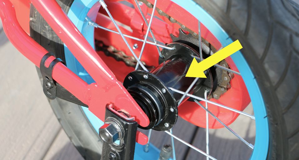 yellow arrow pointing to a black coaster brake hub on a kids bike