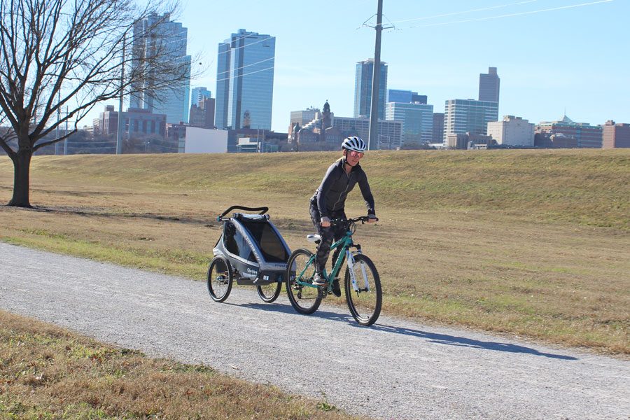 Mom pulling Qeridoo Kidgoo 1 trailer with Fort Worth cityscape behind her