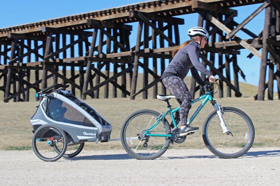 Mom pulling Queridoo Kidgoo trailer on gravel path 