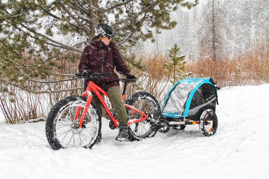 Woman on fat bike pulling Burley trailer behind her with ski kit attachment