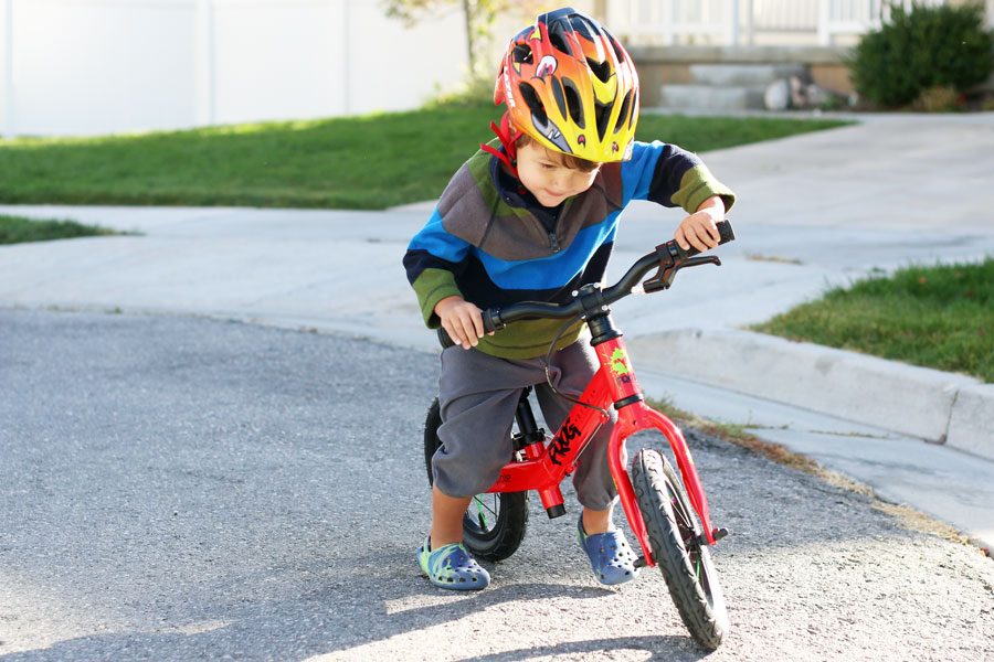 boy turning the handlebars on a frog tadpole balance bike