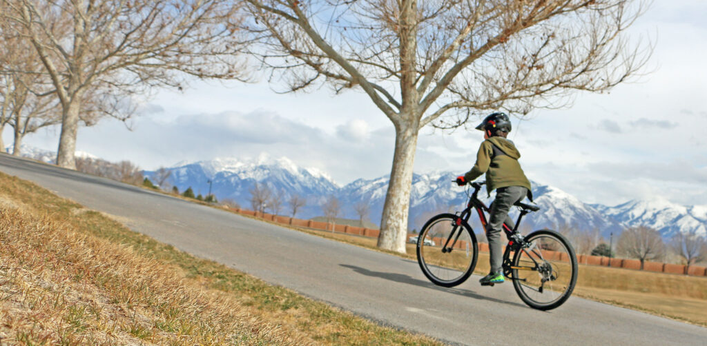Boy riding the 24 inch Polygon Ultralight bike up a steep paved biking path