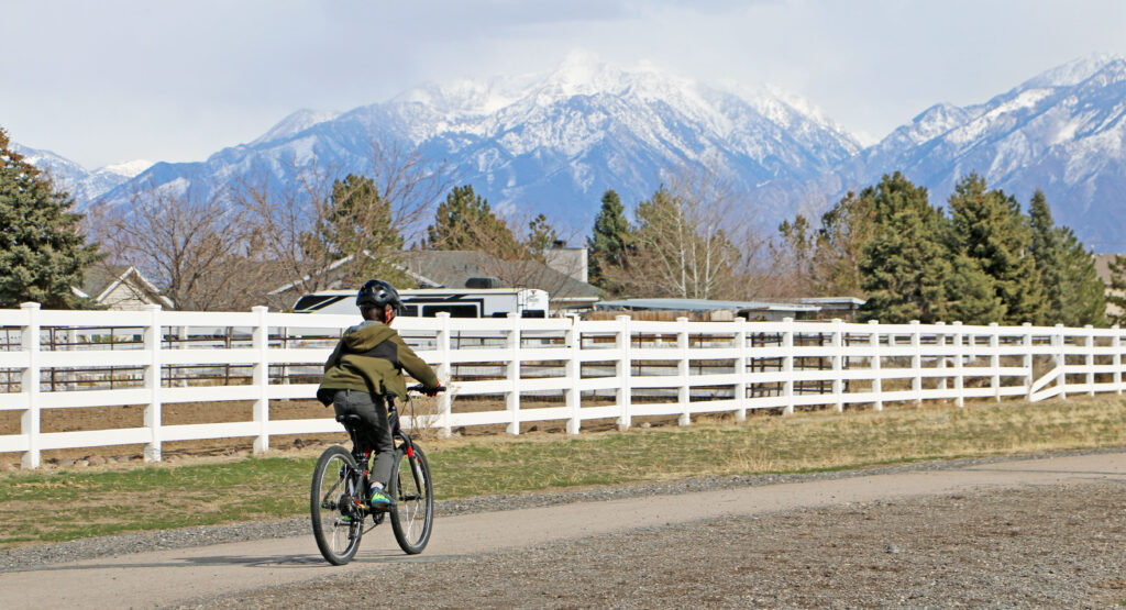 boy riding the 24 inch polygon kids bike on a paved path with the mountain in the distance