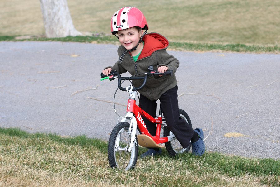 Boy pushing the woom 1 plus up a grassy hill